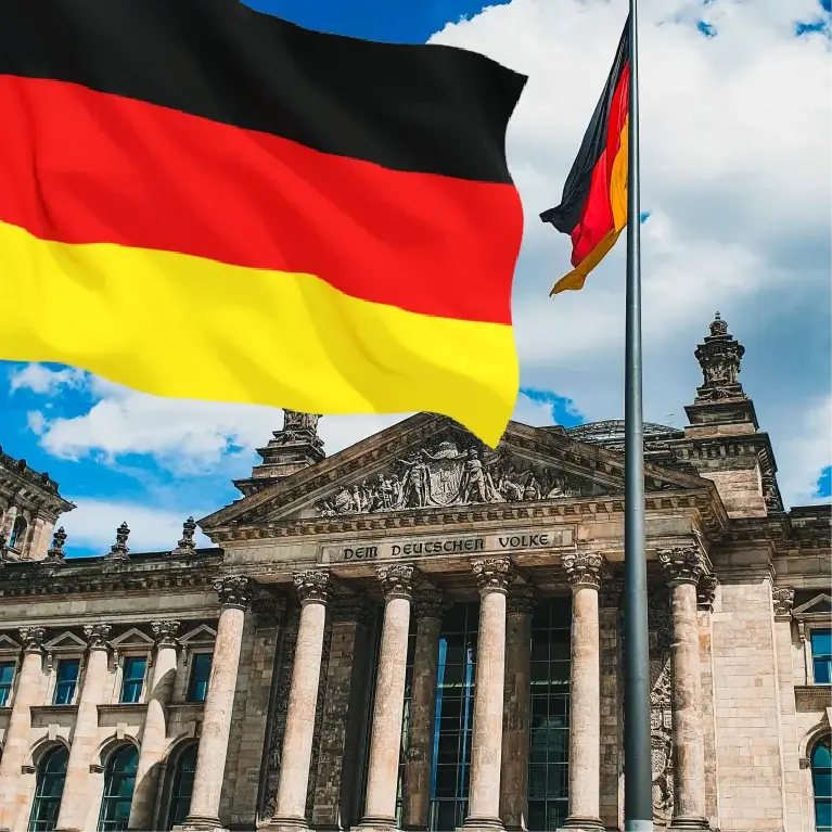 Image of the German flag waving with the Berlin skyline, including the Brandenburg Gate and TV Tower, in the background.